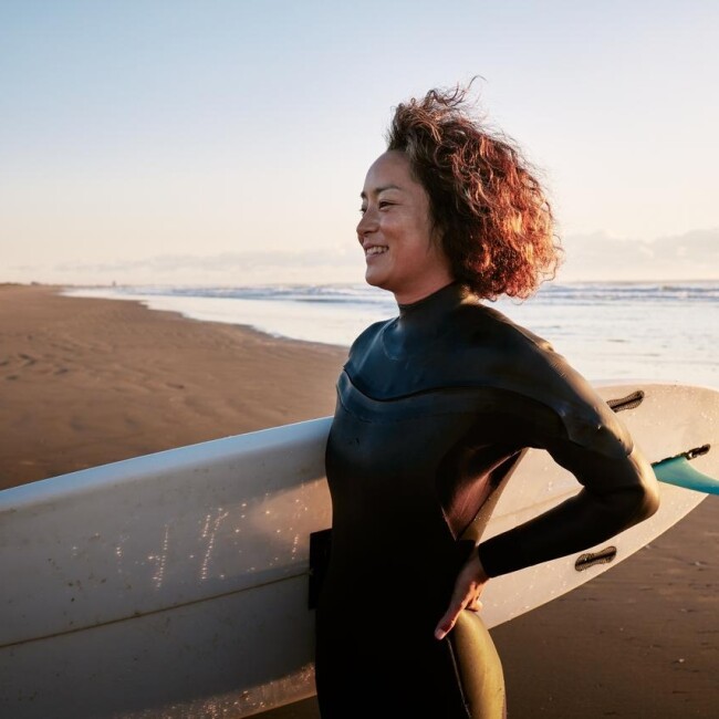 Mulher com prancha de surfe na praia